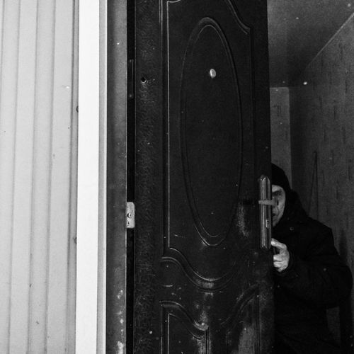 Free A suspenseful black and white photo of a person partly hidden behind an open door. Stock Photo
