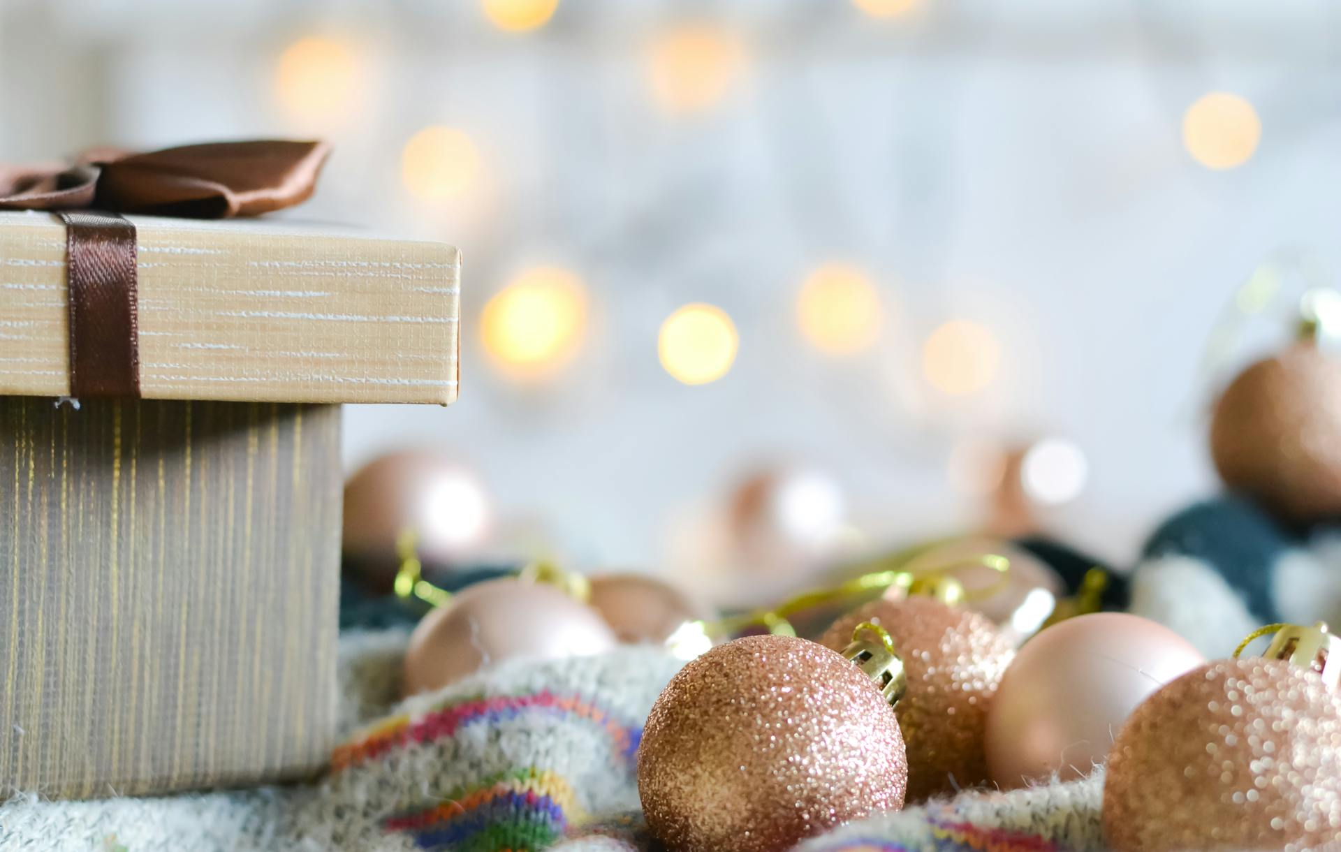 A beautifully wrapped gift box with sparkling ornaments and festive bokeh lights.