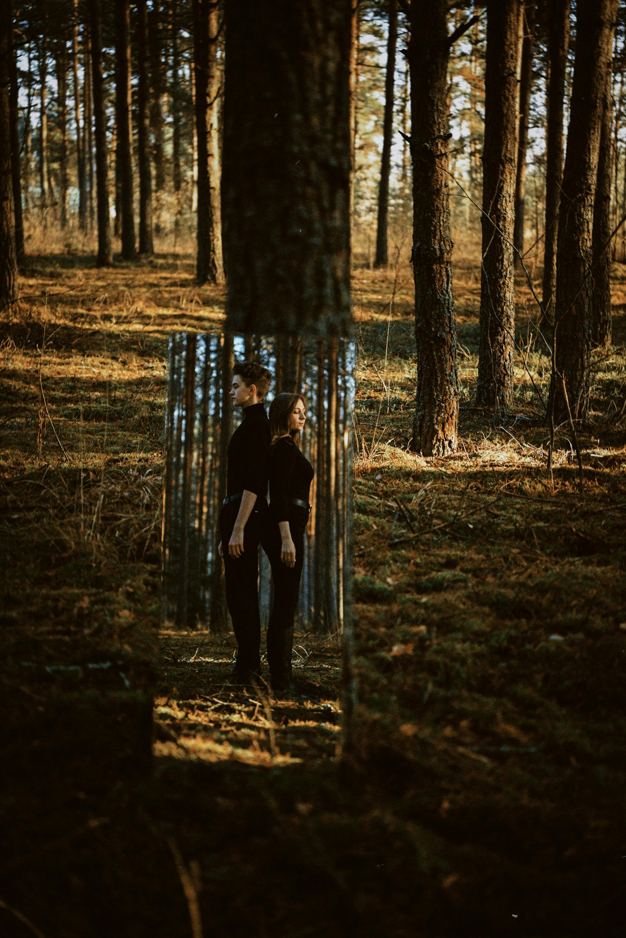 A couple's reflection in a mirror placed within an autumn forest creating a surreal effect.