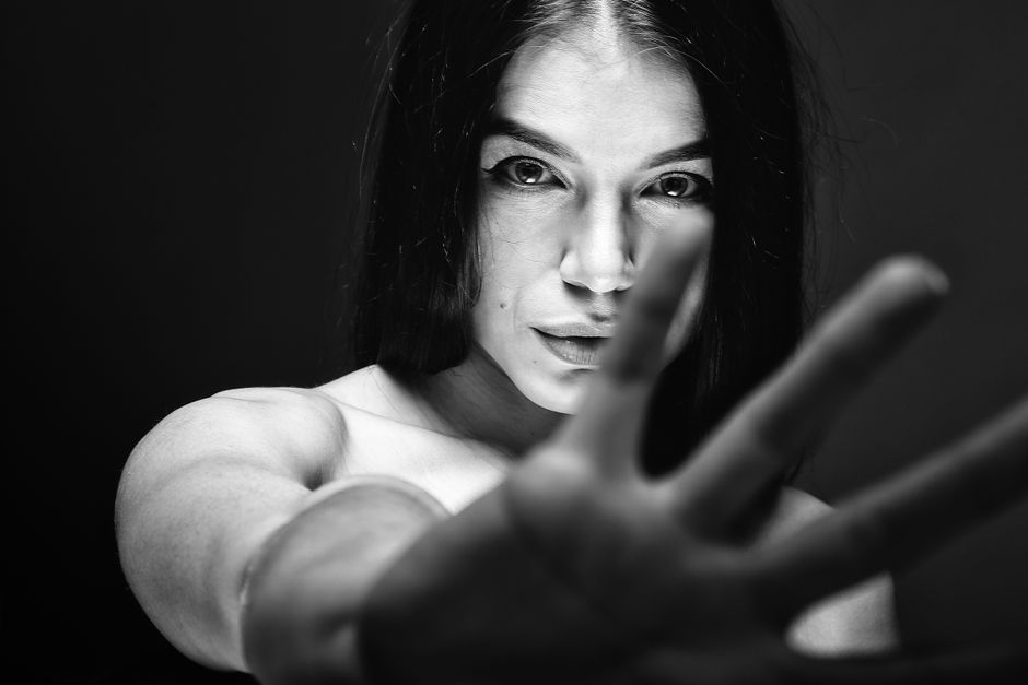 Captivating black and white portrait of a woman reaching towards the camera with intense expression.