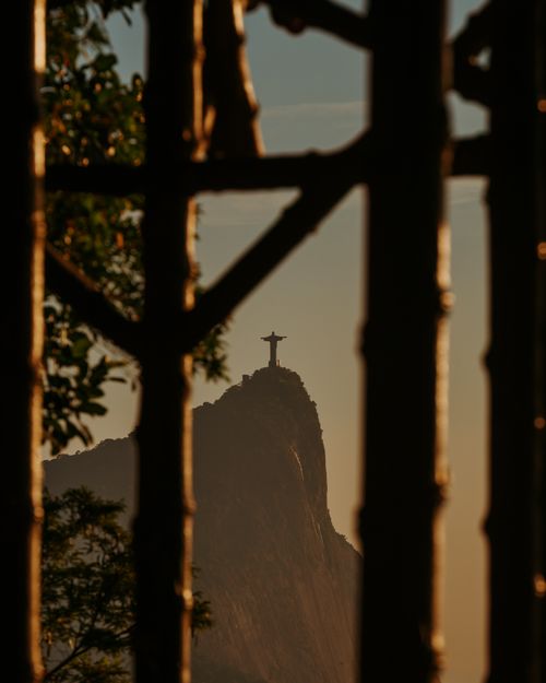 Free Silhouette of Christ the Redeemer statue framed by trees at sunset in Rio. Stock Photo