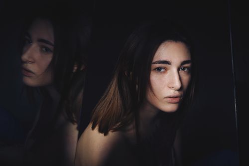 Free Artistic portrait of a woman with mirror reflection, highlighting emotions. Stock Photo