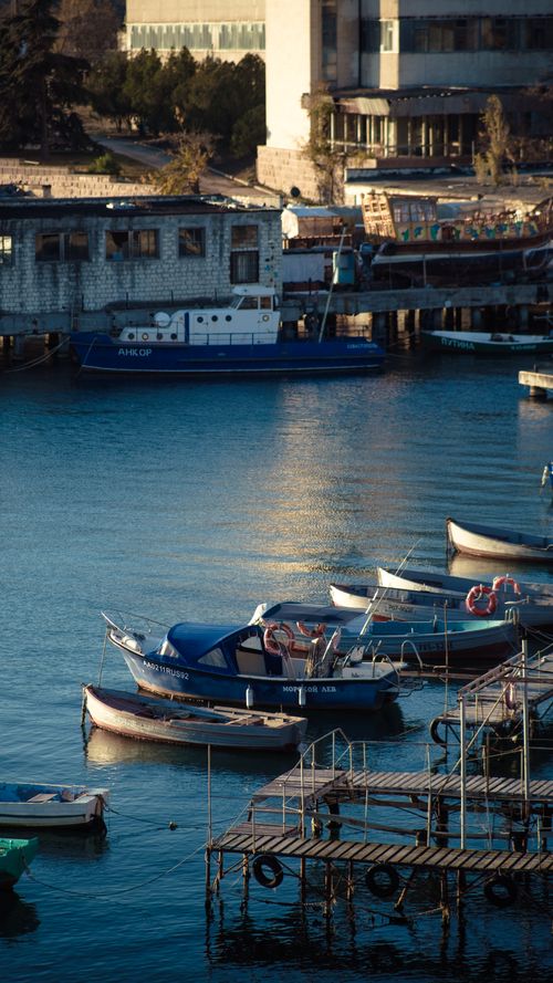 Free Tranquil view of boats docked in a harbor, reflecting the serene twilight sky and rustic architecture. Stock Photo