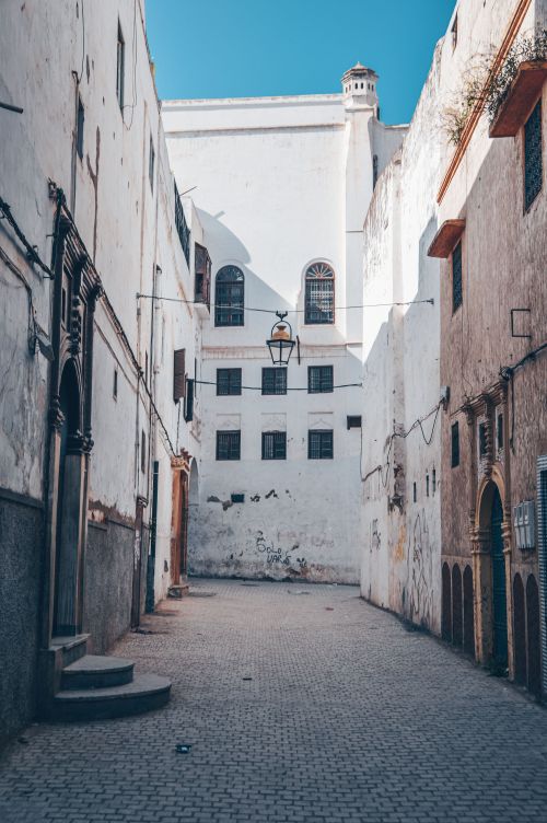 Free Sunlit alleyway in Rabat with traditional buildings and cobblestone path. Stock Photo