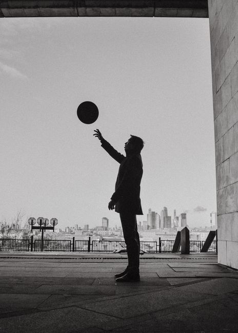 A stylish silhouette of a man tossing a ball with Moscow's city skyline as the backdrop.