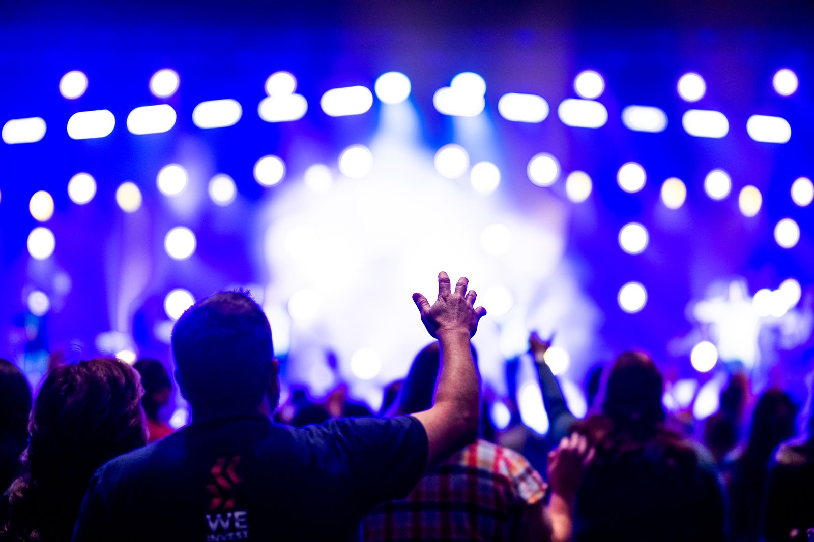 Crowd with raised hands under blue stage lights