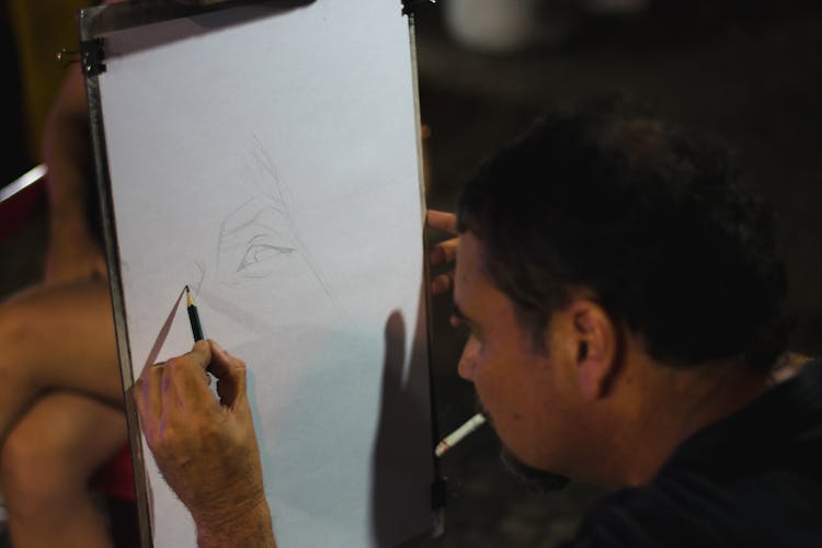 A Man Drawing While Smoking A Cigarette