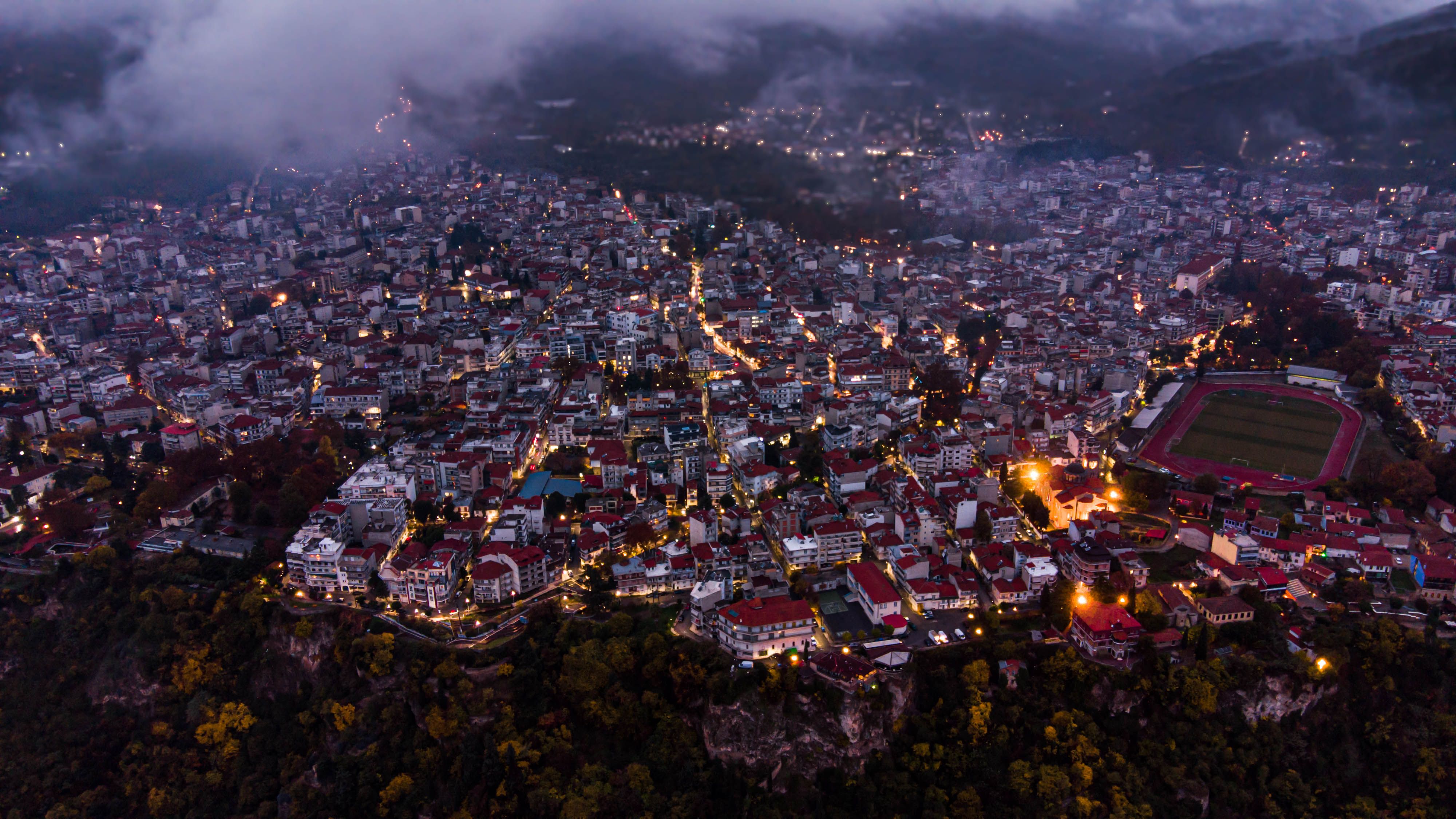 Aerial night view of Edessa, Greece, showcasing city lights and architecture.