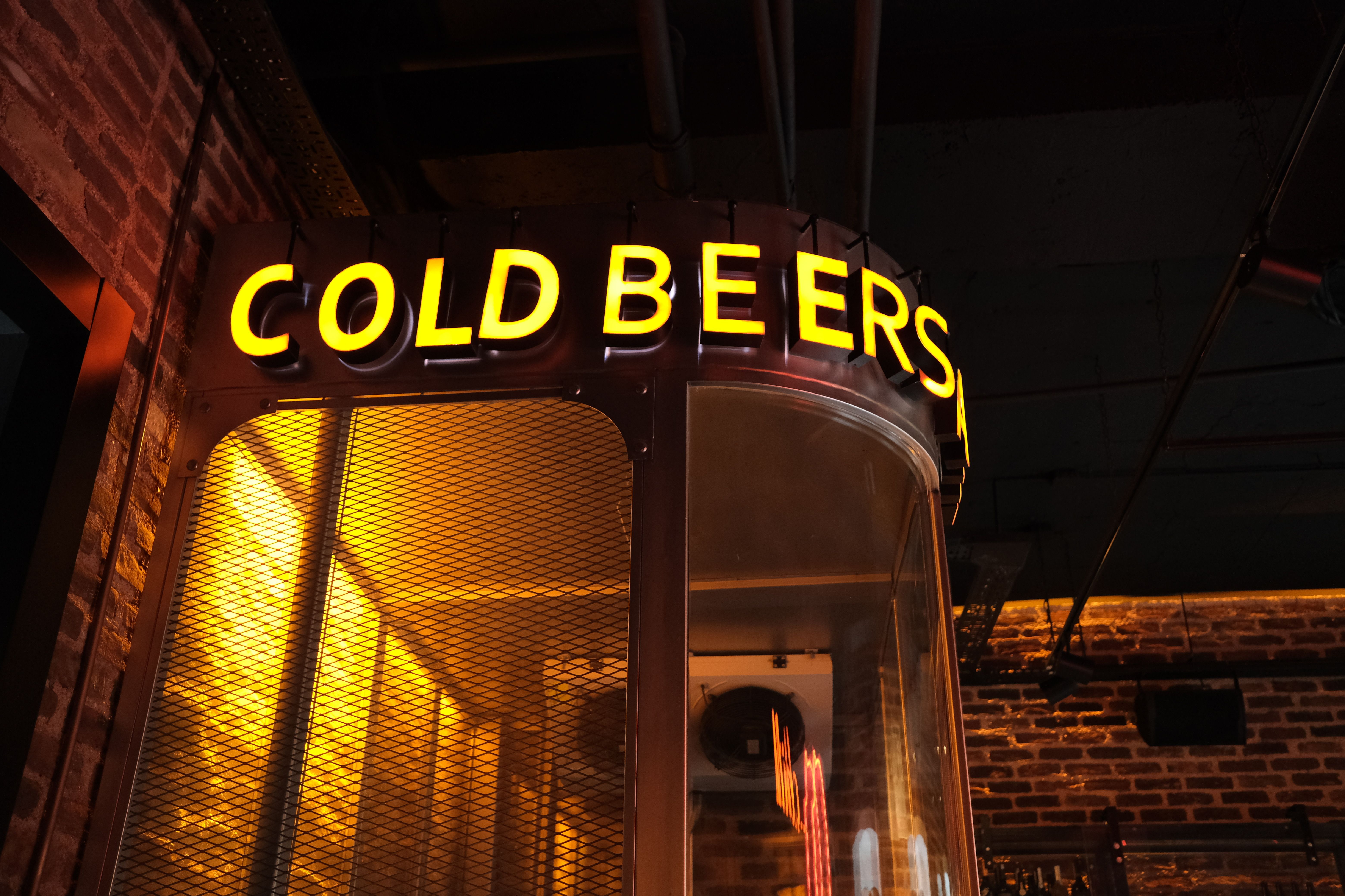 Neon sign with 'Cold Beers' glowing warmly in a cozy bar interior atmosphere.