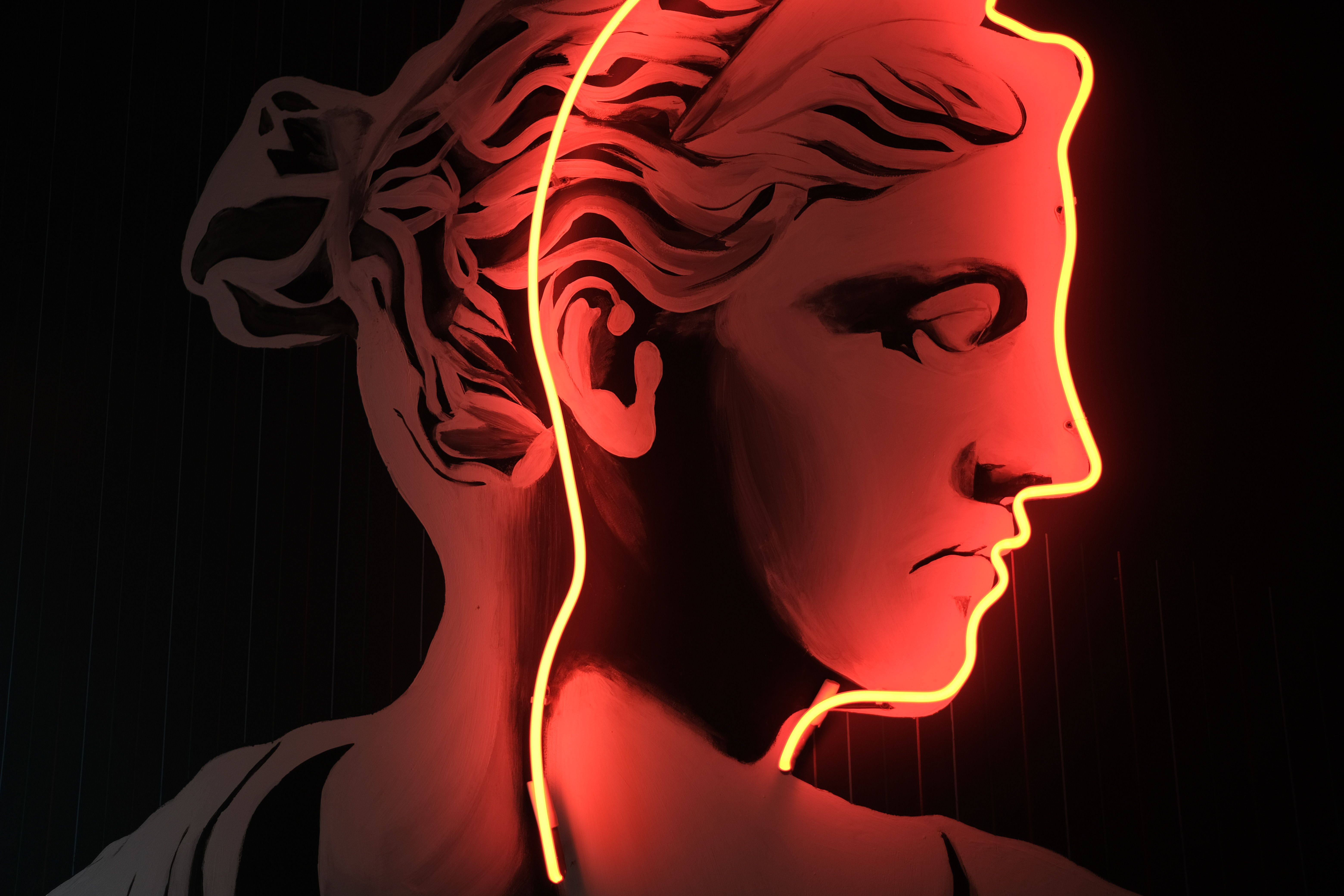 Striking classical art piece enhanced with vibrant orange neon lighting, showcasing artistic contrast.