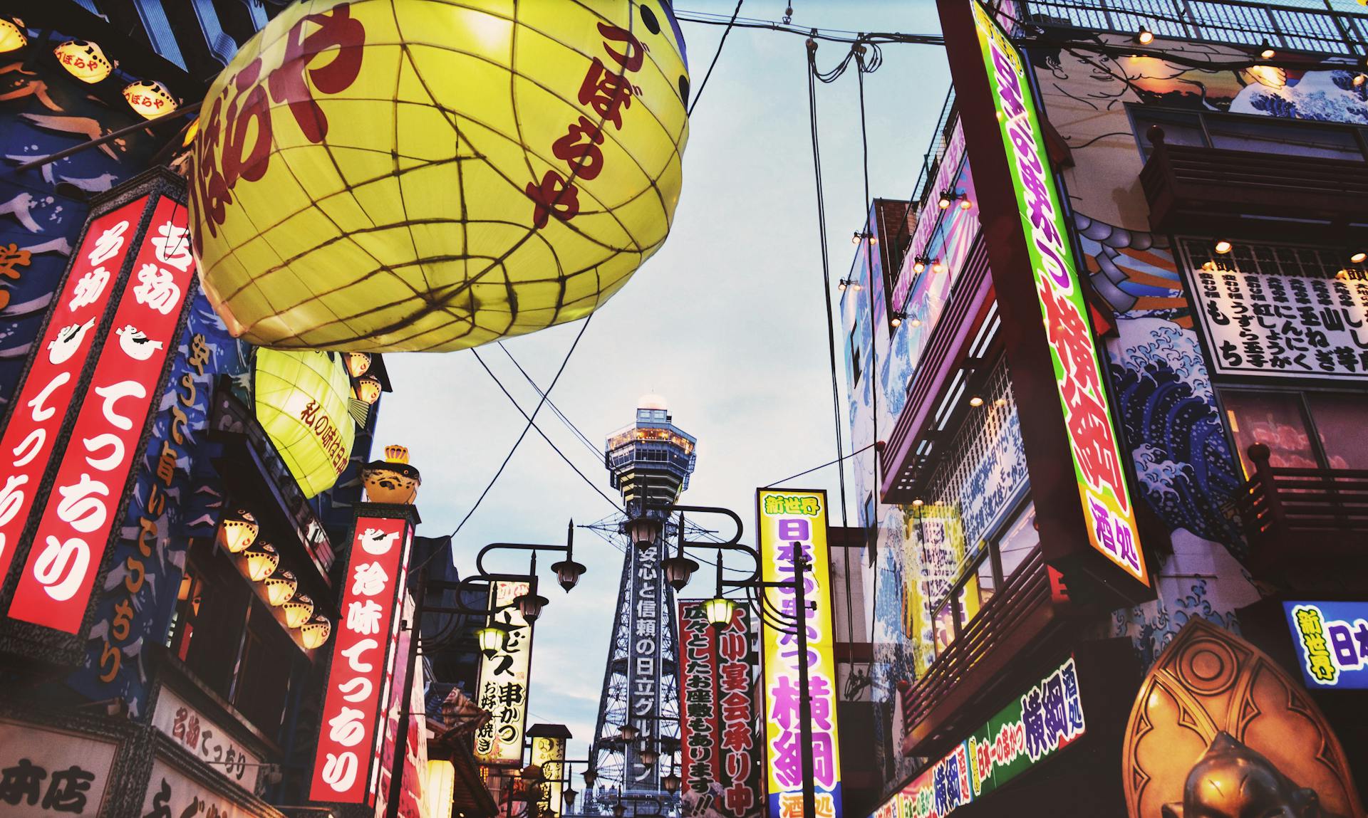 Colorful neon lights and signs illuminate a bustling street in Osaka, Japan.