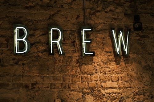 Free Neon 'Brew' sign glowing against an industrial brick wall setting. Stock Photo
