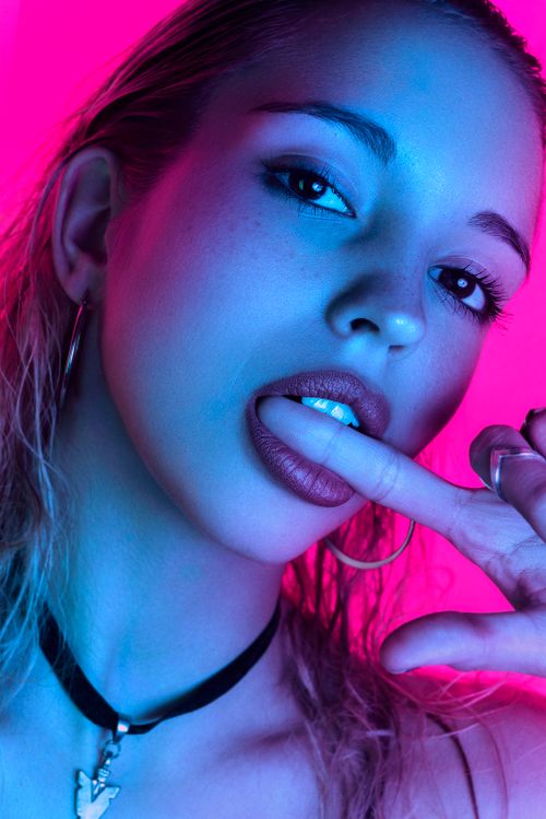 Free Close-up expressive portrait of a woman with vibrant neon lighting, showcasing modern aesthetic. Stock Photo