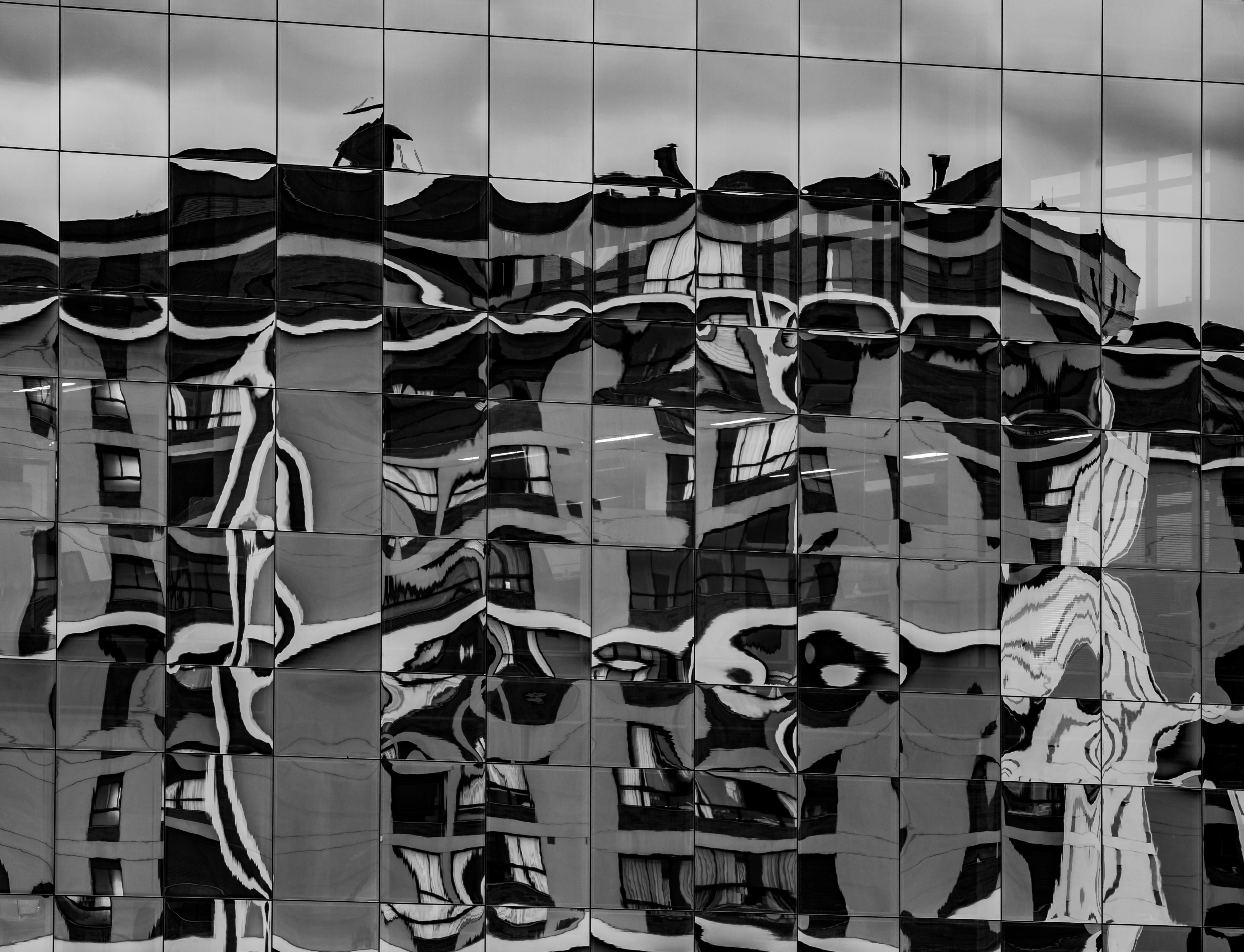 Distorted reflection of building on a glass facade captured in grayscale, SC, Brazil.