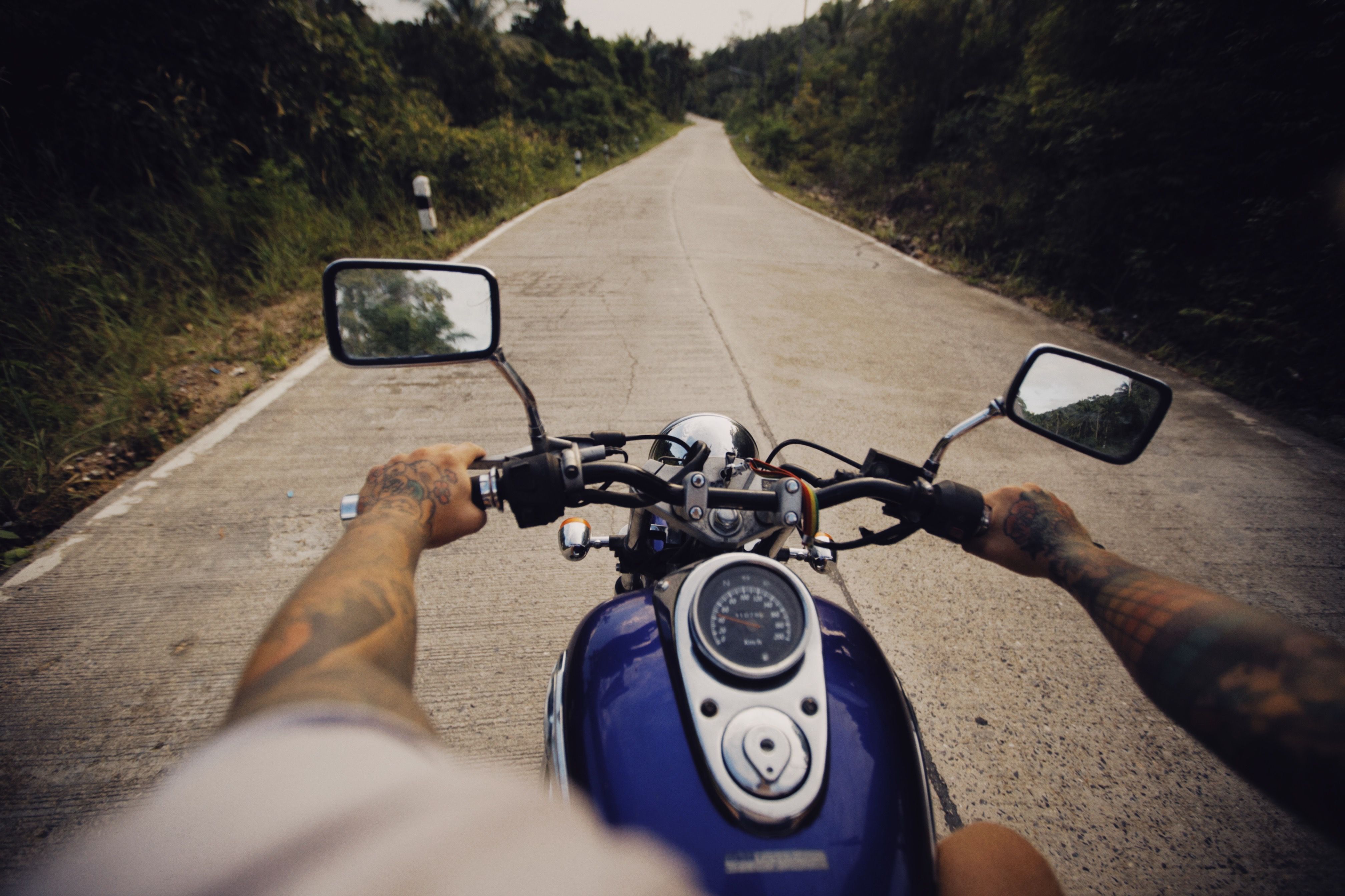 Un motociclista tatuato percorre una pittoresca strada rurale, offrendo un senso di avventura.