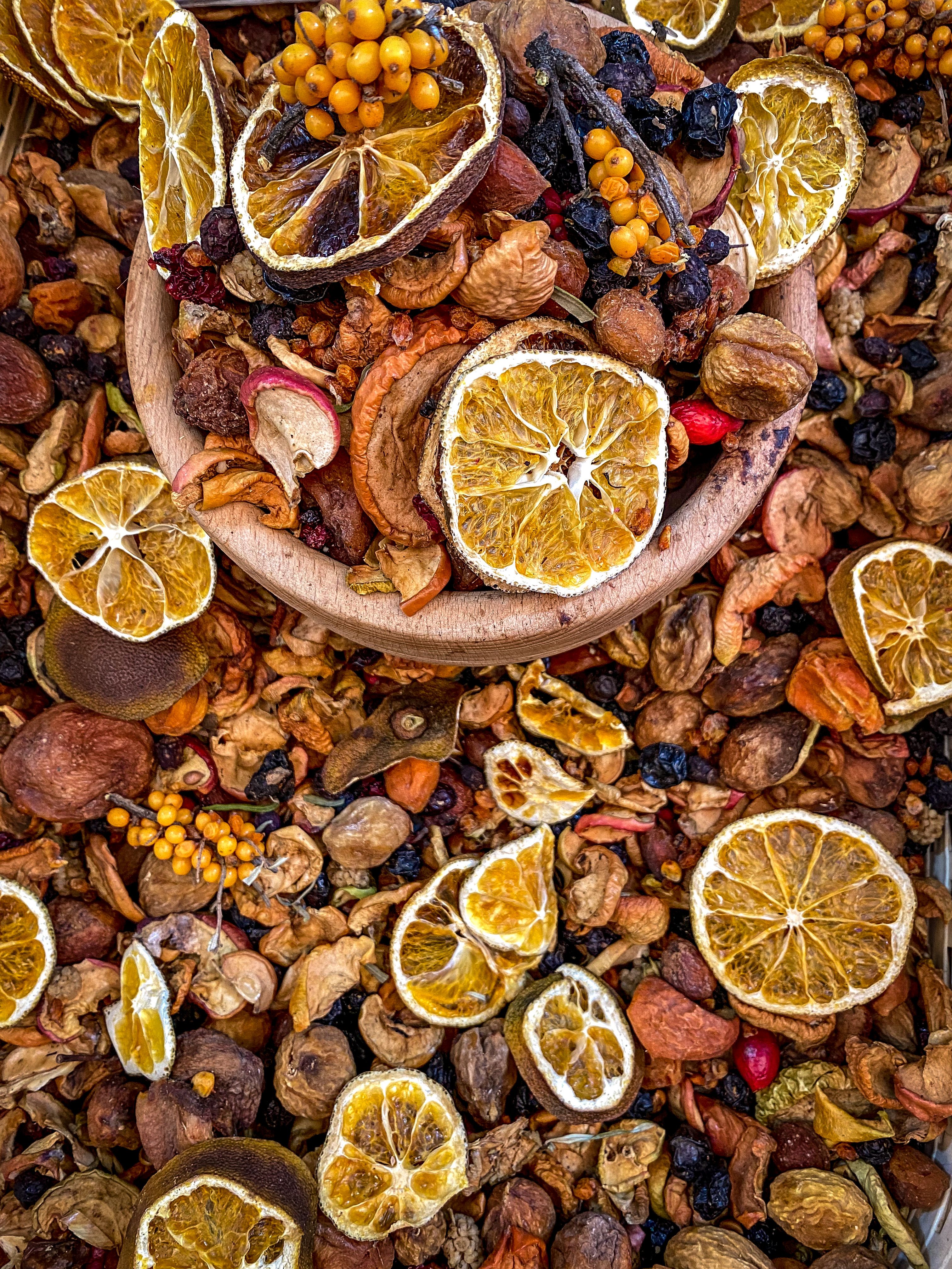A colorful assortment of dried fruits including oranges, berries, and nuts displayed in a wooden bowl. - Where to Buy Dry Fruits Online in Pakistan