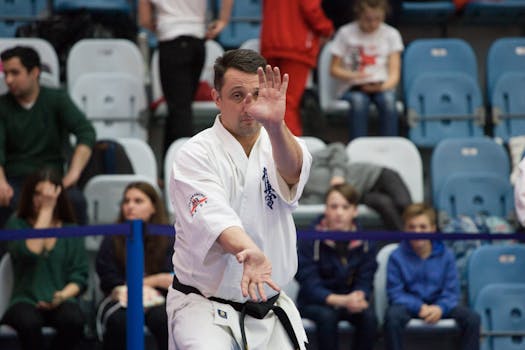 Karate master performing kata in sports arena during competition event.