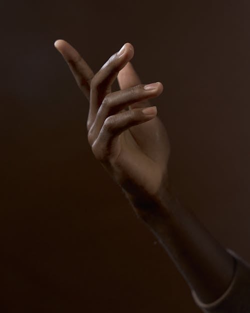 Close Up Photo of Human Hand on Brown Background