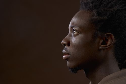 Free Studio portrait profile of a young black man against a brown background. Stock Photo