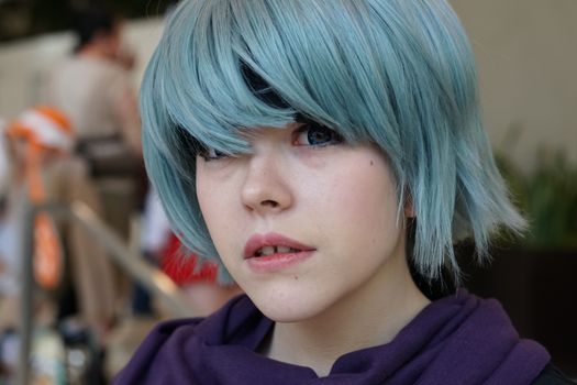 A captivating portrait of a young person wearing a blue wig in cosplay attire.