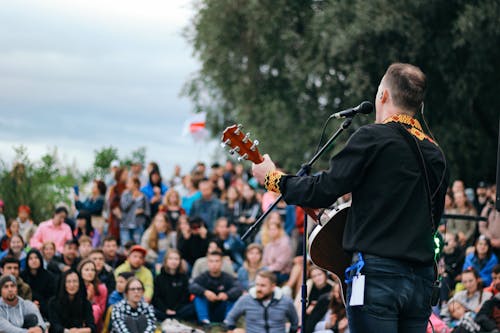 A Man in Black Jacket Playing Guitar