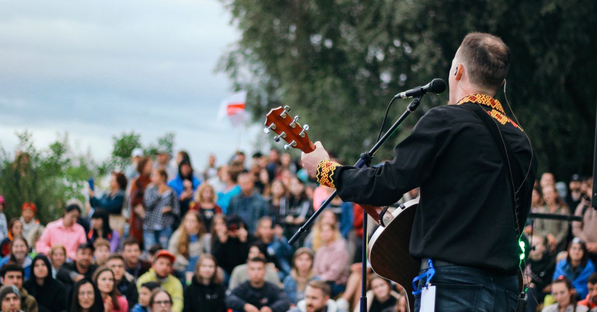 A lively outdoor concert featuring a man playing guitar with an engaged audience in attendance.