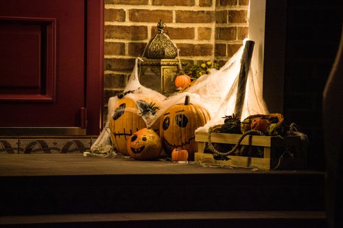 Free Festive Halloween decor featuring carved pumpkins and cobwebs at a doorstep. Stock Photo