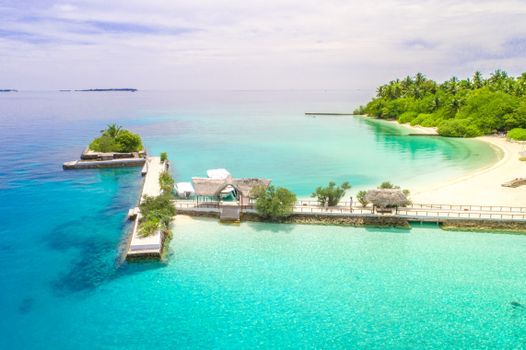 High angle shot of tropical Maldives resort with clear turquoise water and sandy beach.