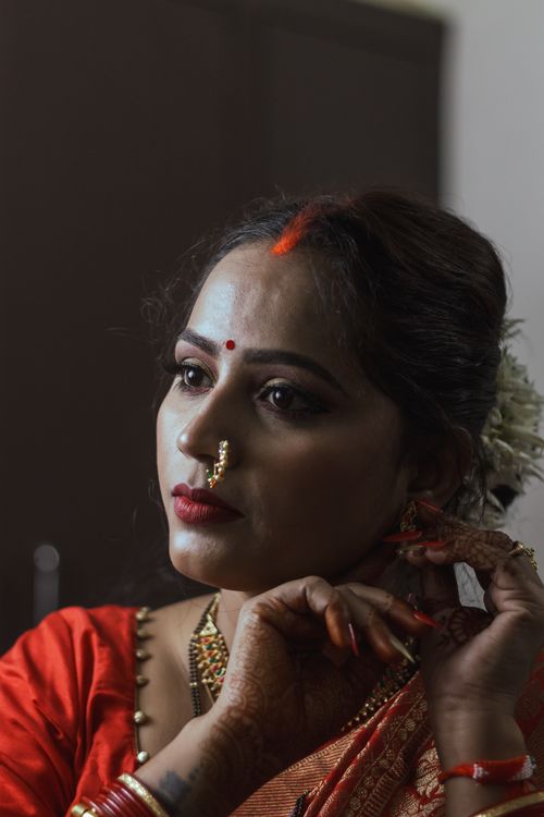 Free Portrait of a woman in traditional attire, adjusting earrings, showcasing Indian culture. Stock Photo