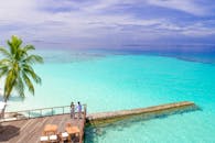 一对夫妇在马尔代夫的热带甲板上，俯瞰着碧绿的海水，享受着宁静的时刻