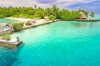 鸟瞰一对夫妇在马尔代夫的一个热带岛屿度假村放松，周围环绕着清澈的海水