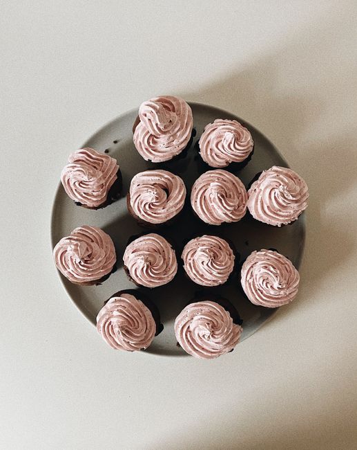 An aerial view of beautifully arranged cupcakes topped with pink icing on a plate.