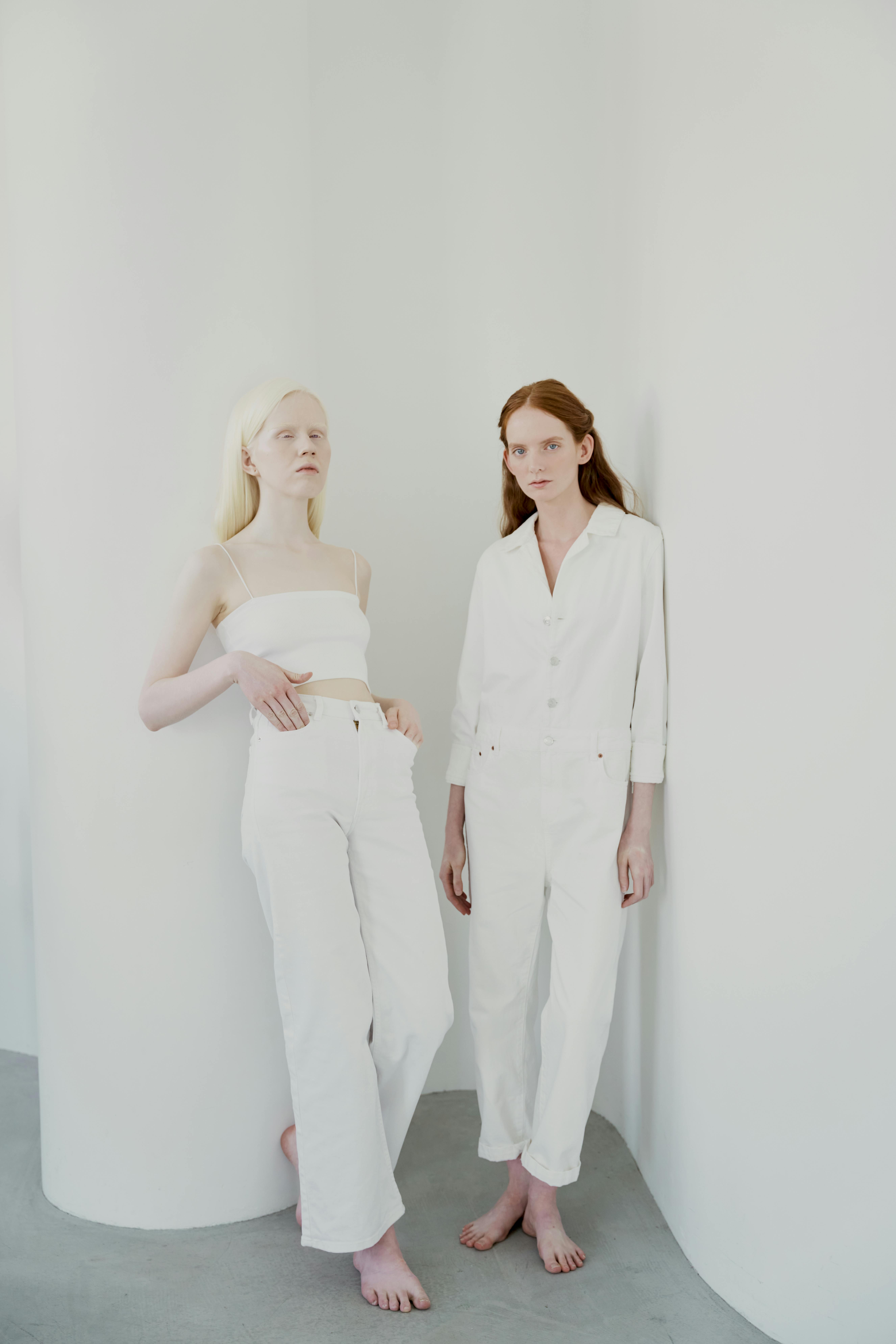 Elegant minimalistic portrait of two women leaning against a white curved wall