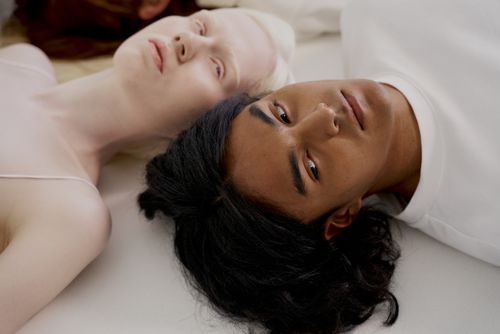 Free Close-up of diverse individuals lying on a white surface in a studio setting. Stock Photo
