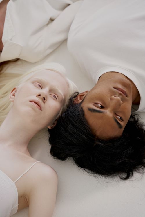 Free An artistic portrait of an albino and Asian individual lying side by side, showcasing diversity. Stock Photo