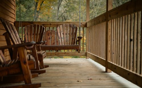 Free A serene wooden porch featuring a rustic hanging swing amidst autumnal foliage. Stock Photo