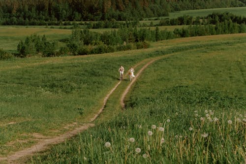 Man and Woman Riding Down Dirt Road With Bikes