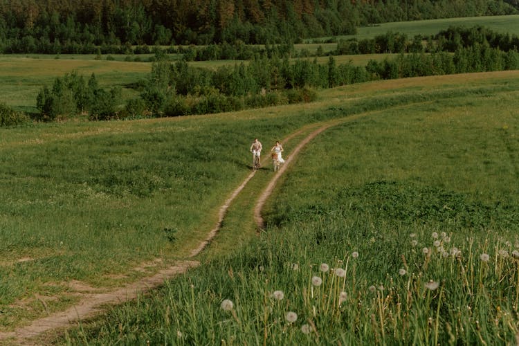 Man And Woman Riding Down Dirt Road With Bikes