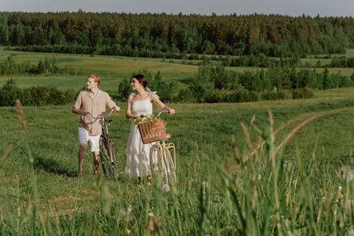 Man and Woman Standing in a Field with Bikes