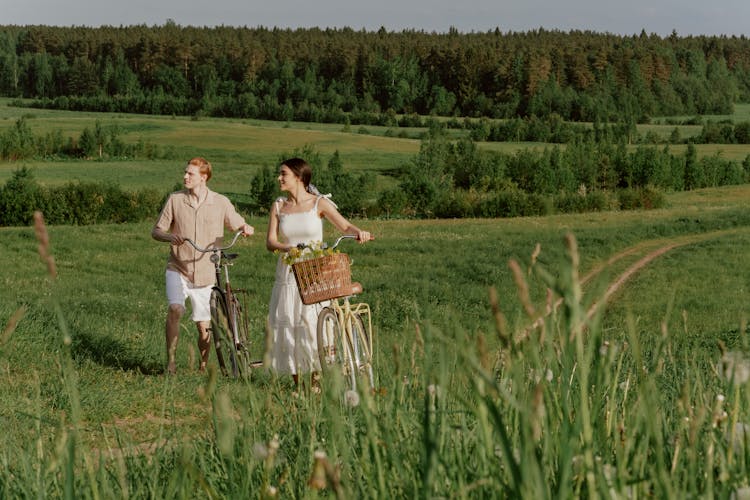 Man And Woman Standing In A Field With Bikes