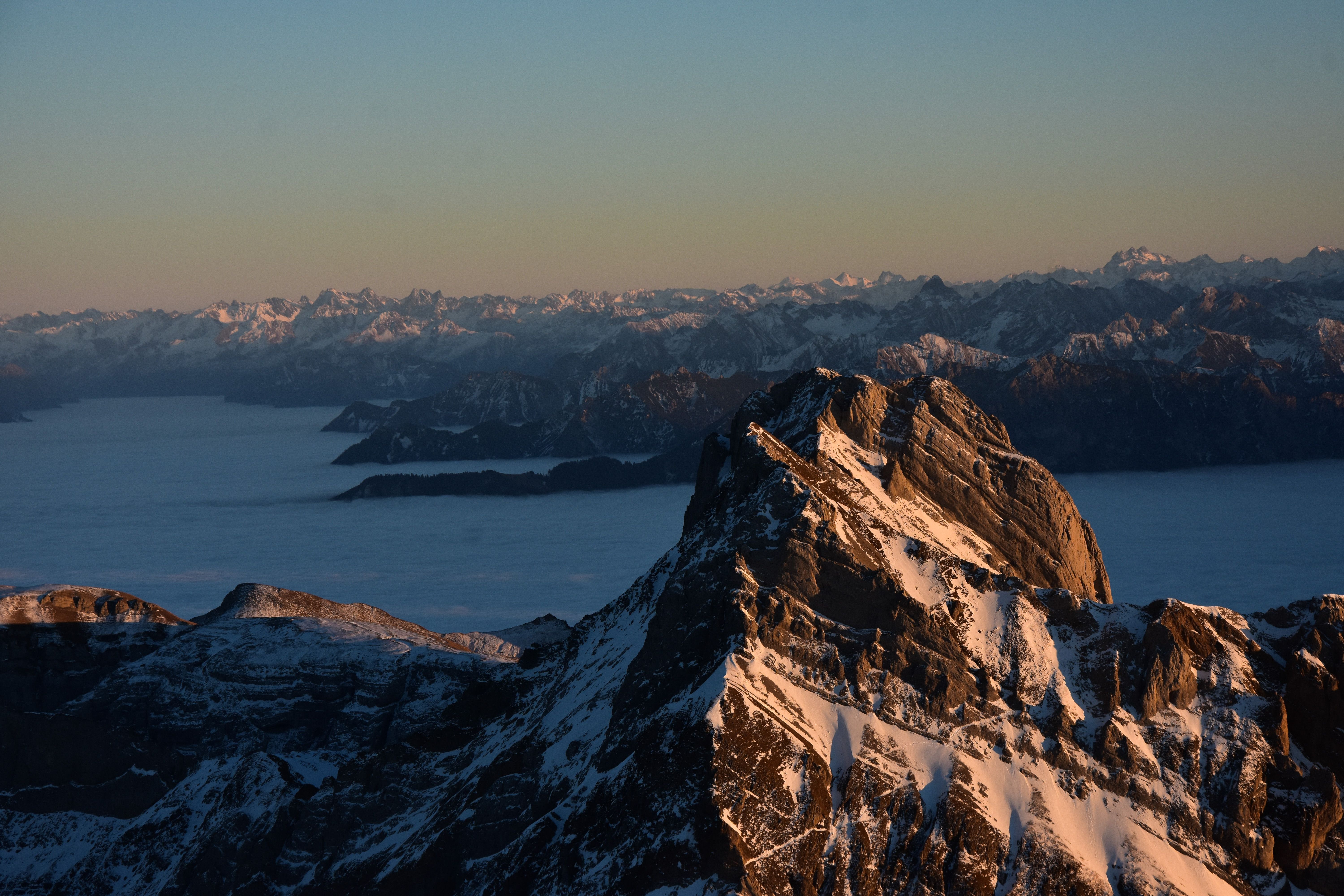 Breathtaking aerial view of snow capped mountains and misty lake at sunrise in Schwende, Switzerland.