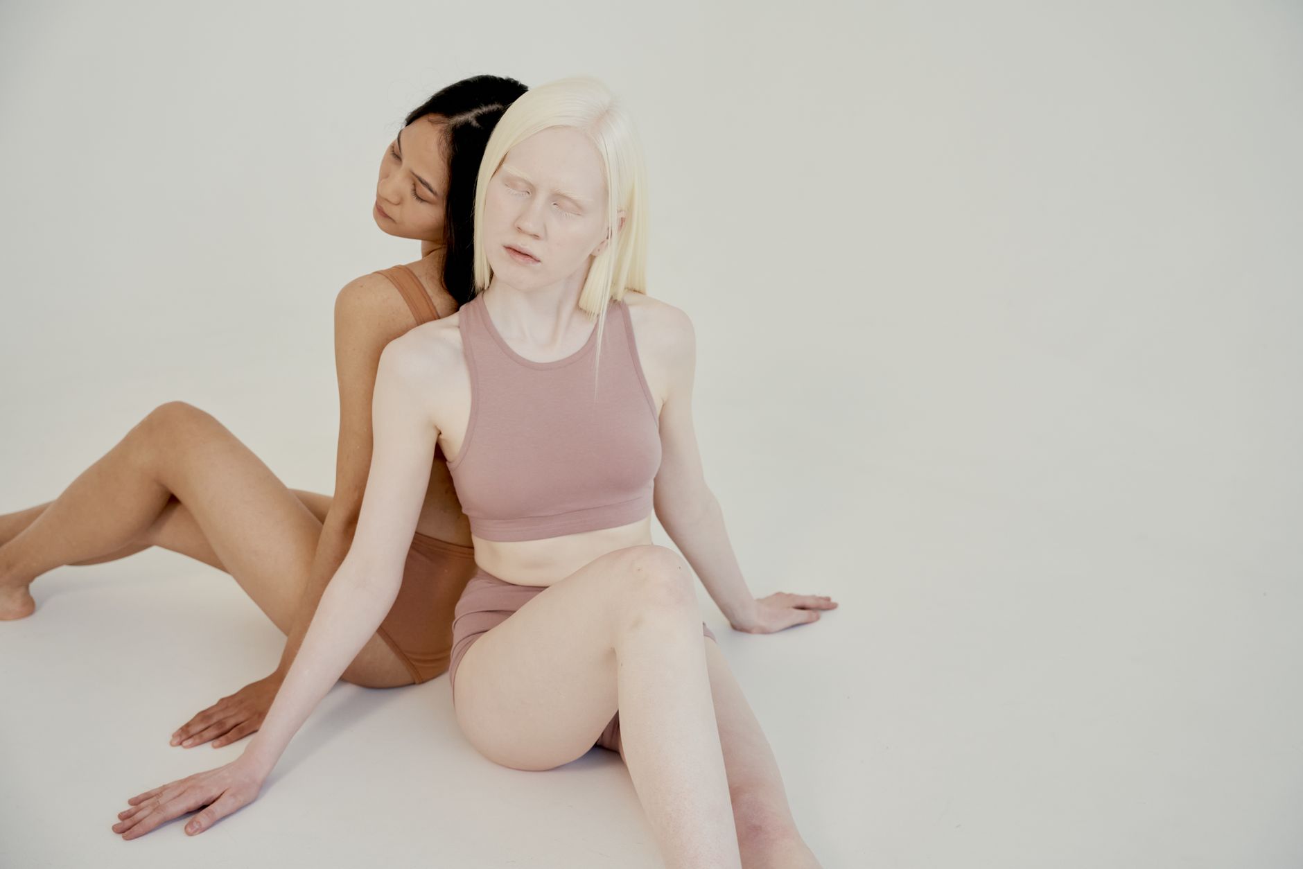 Two diverse women in a serene studio setting, showcasing natural beauty and diversity.