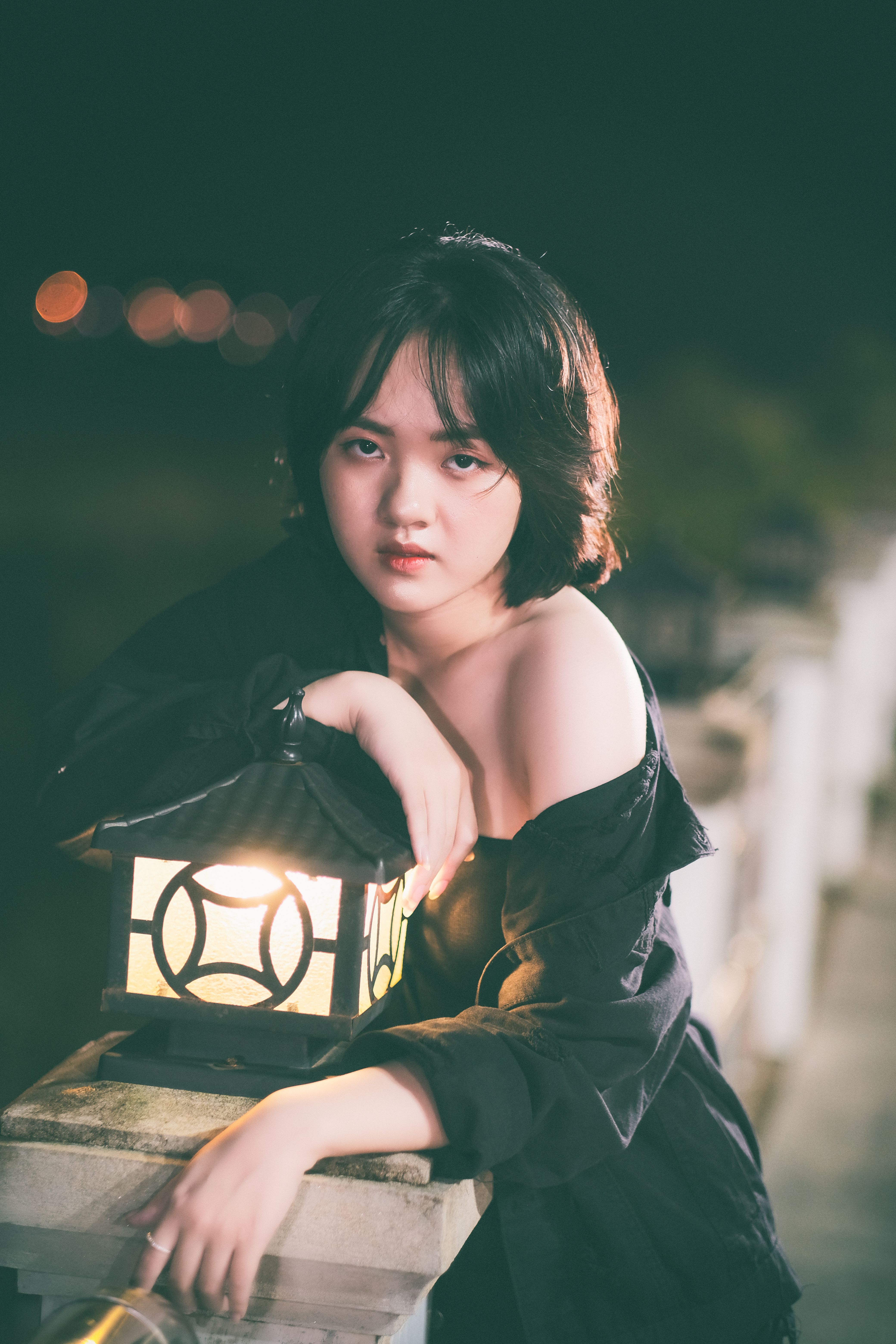 Portrait of woman in black posing by lamp with soft light at night.