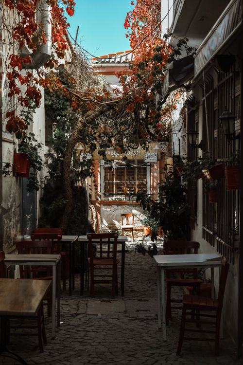 Free Cozy outdoor cafe in a picturesque alleyway with red ivy in Balıkesir, Turkey. Stock Photo