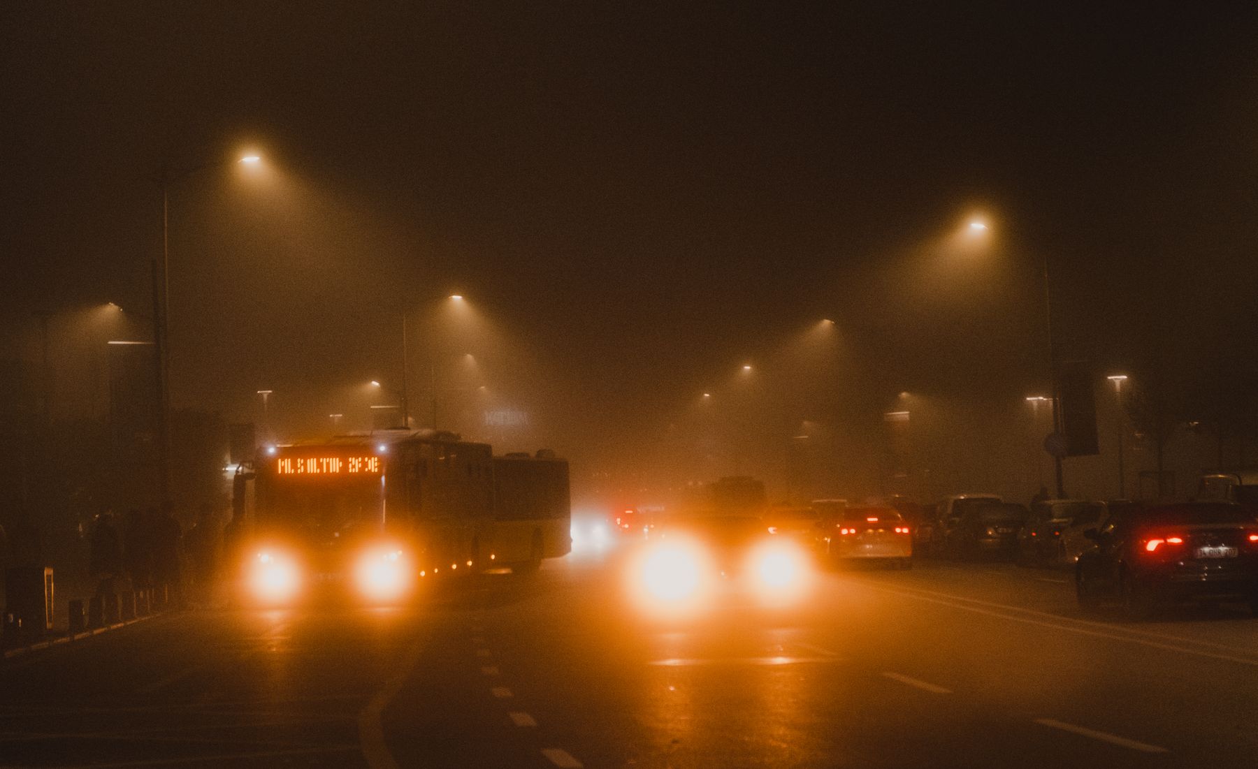 Luces de vehículos atravesando la niebla en una vía de acceso