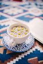 Cup of Aromatic Camomile Tea on Ornamental Tablecloth