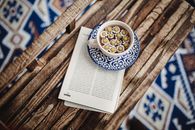 Cup of Camomile Infusion and Magazine Laying on Wooden Bench