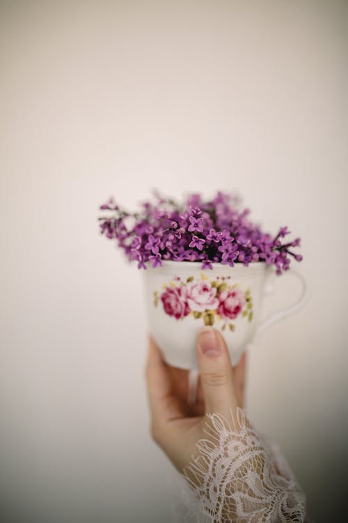Unrecognizable Female Hand Holding Ornamental Vintage Cup with Lilac Flowers
