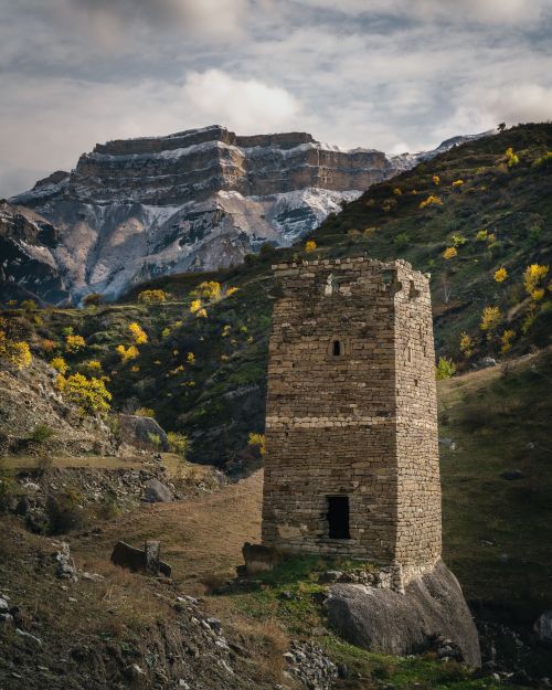 Free A lonely stone tower set against a majestic mountain backdrop. Stock Photo