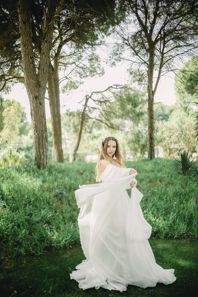 Young Woman In Park Presenting White Wedding Dress 